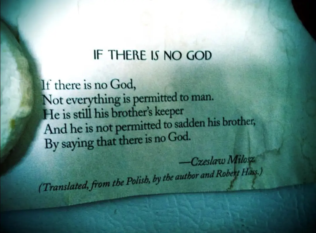 A close-up of a crumpled, aged paper with a poem titled 'IF THERE IS NO GOD' by Czeslaw Milosz, printed in black serif font…