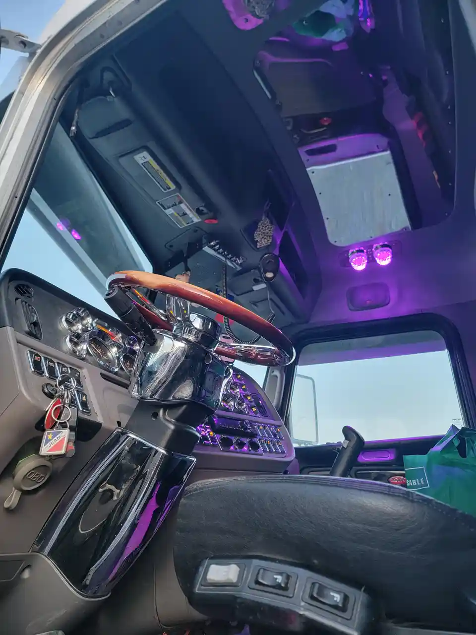 A low-angle shot inside a truck cab, showing a chrome and wood steering wheel, a dashboard with numerous gauges and buttons…