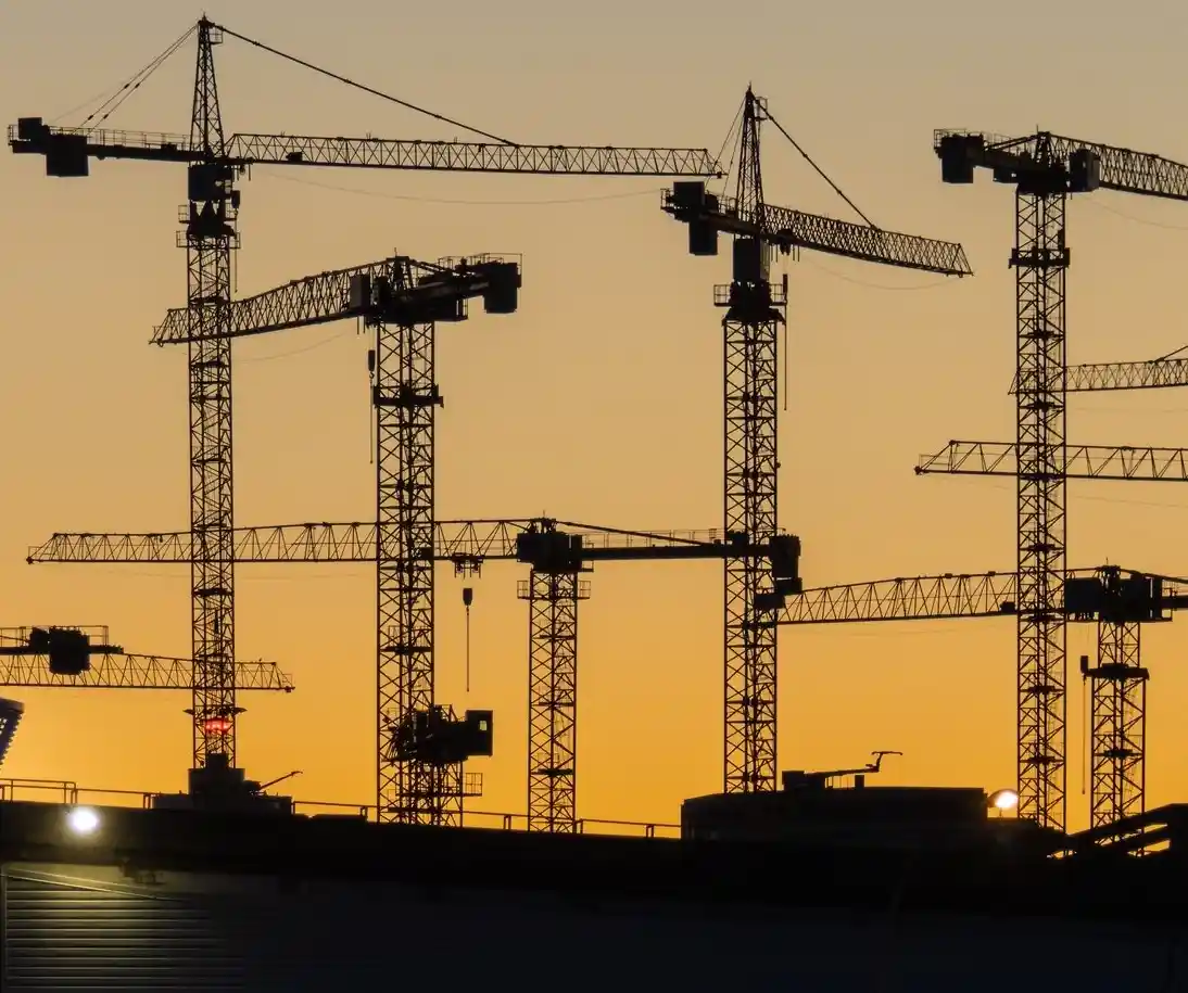 A silhouette of multiple construction cranes against a warm orange sunset sky, with the overlaid text reading 'i'm not lazy…