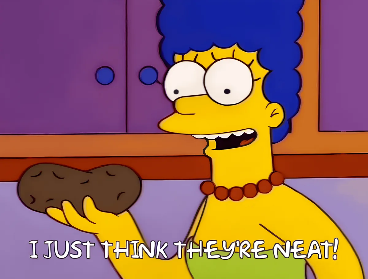 Marge Simpson holds a potato with a delighted expression, standing in front of purple cabinets. The overlaid text reads 'I…