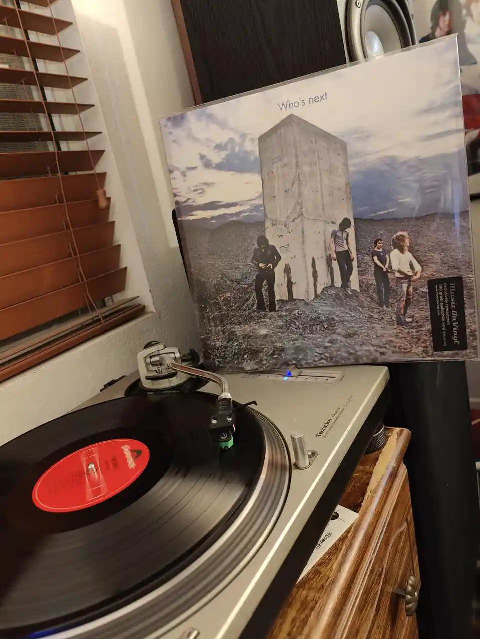 A vinyl record spins on a Technics turntable, with the album cover for The Who's 'Who's Next' leaning against it. The cover…