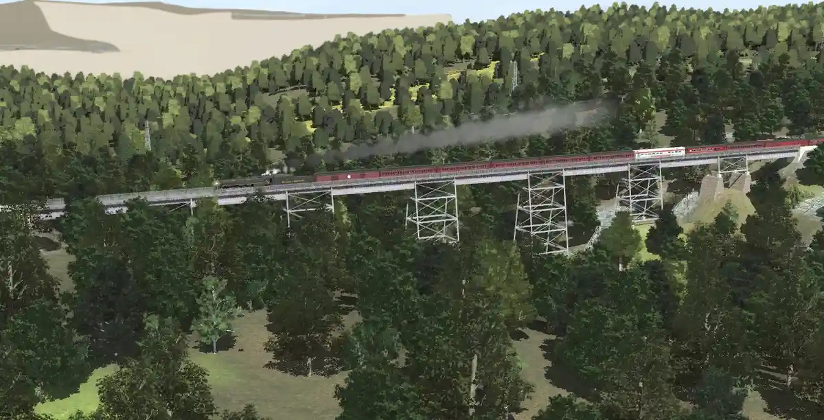 A screenshot from a train simulation game shows a red steam locomotive pulling passenger cars across a metal trestle bridge…