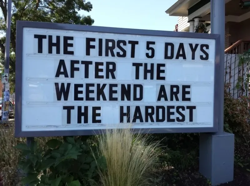 A white light-up sign with black lettering reads 'THE FIRST 5 DAYS AFTER THE WEEKEND ARE THE HARDEST' and is mounted on a…