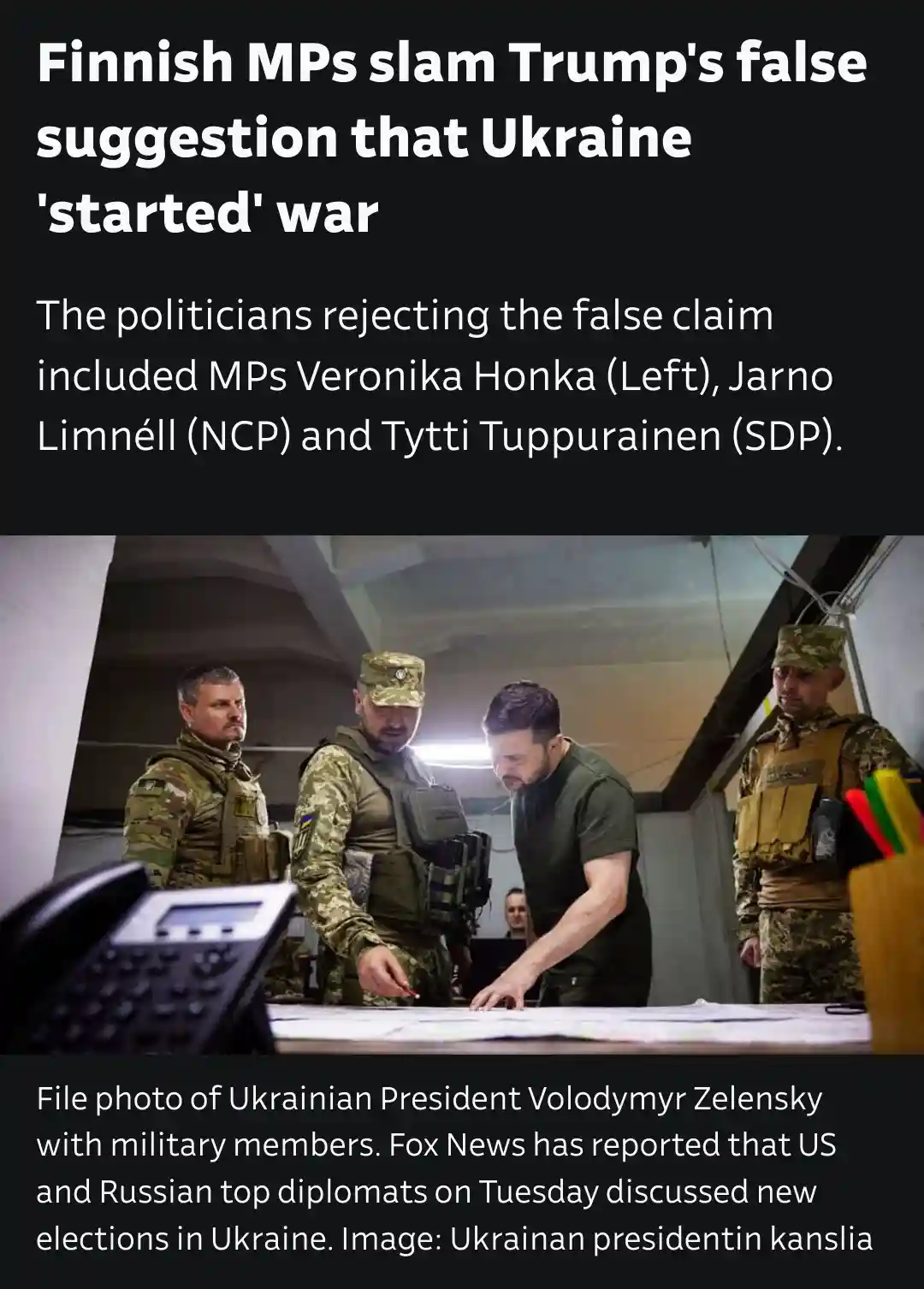 The image shows Ukrainian President Volodymyr Zelensky in a military setting, surrounded by uniformed personnel, examining a…