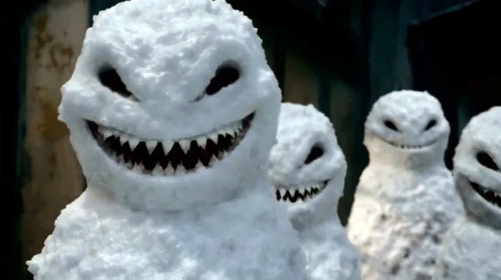 A group of menacing, snow-covered humanoid figures with jagged, toothy grins and hollow black eyes stare forward. The…