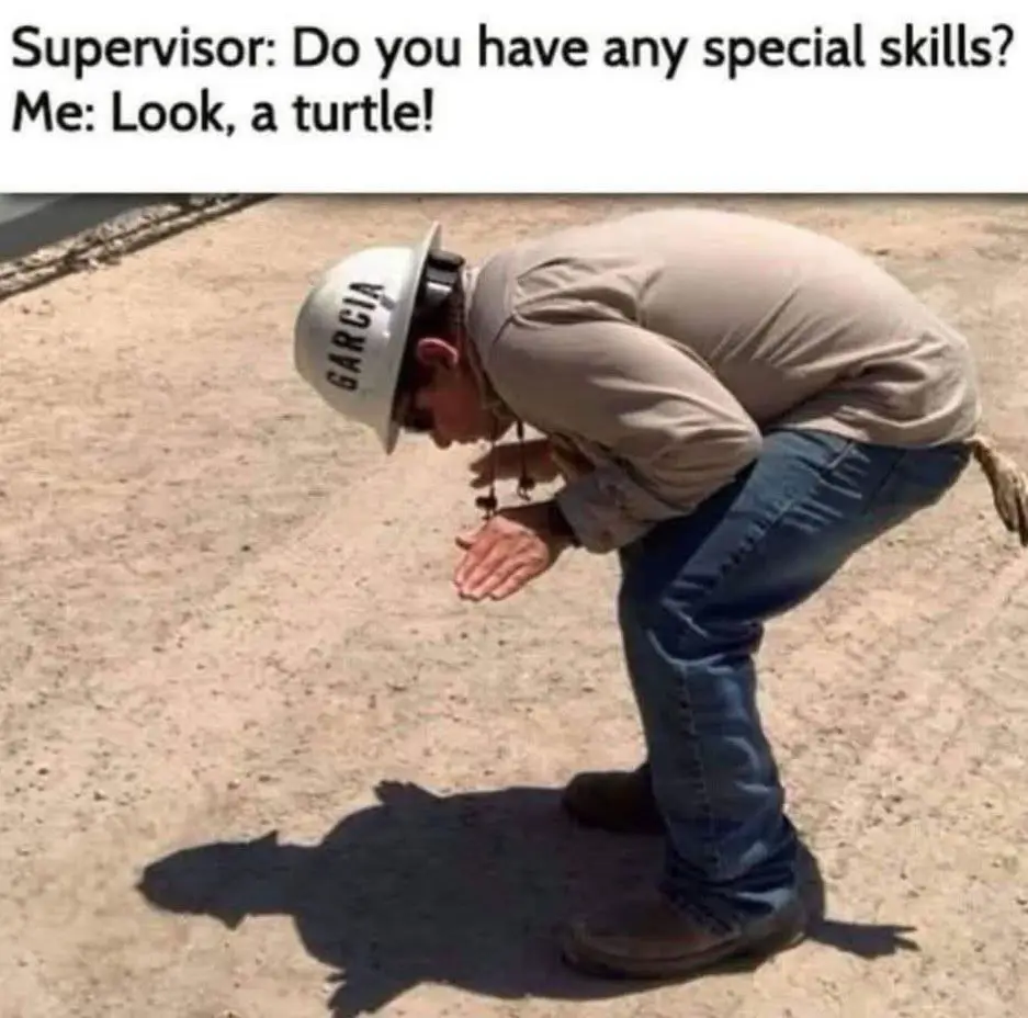 A man wearing a white hard hat labeled 'GARCIA' and blue jeans is bent over on a dirt ground, gesturing with his hands as if…