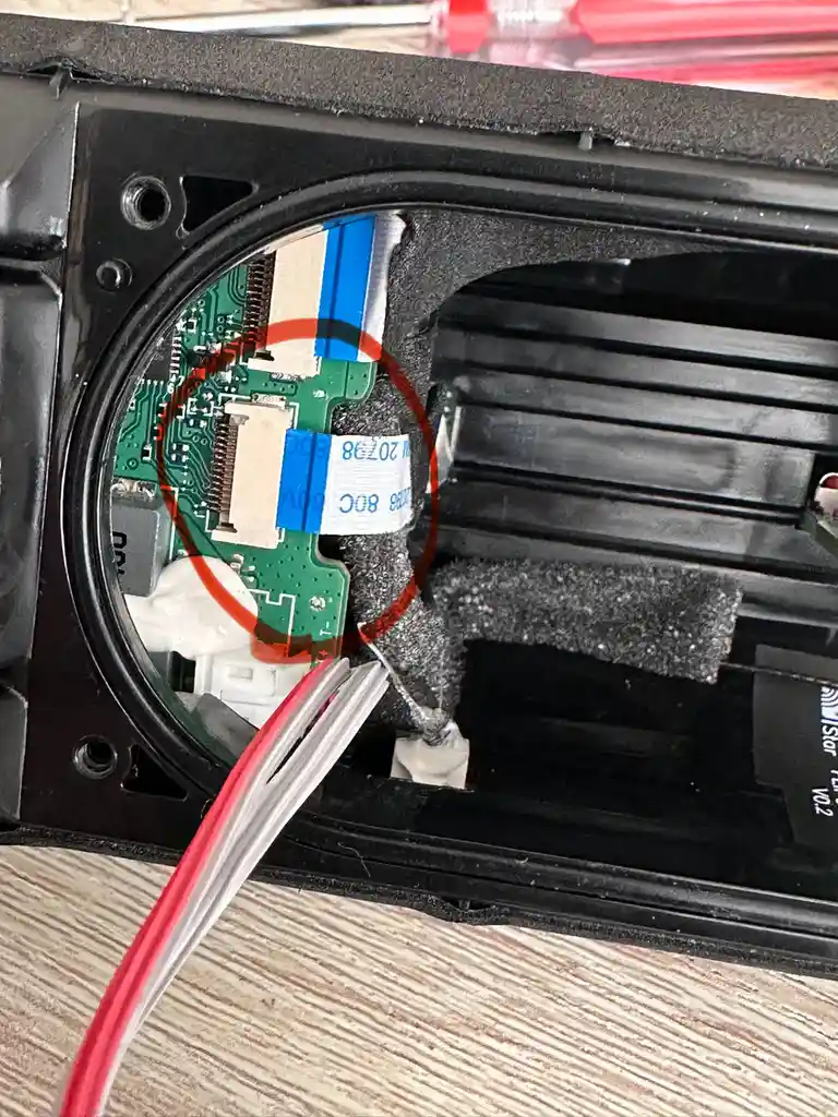 A close-up photo of the inside of an electronic device shows a green circuit board with a red circle drawn around a…
