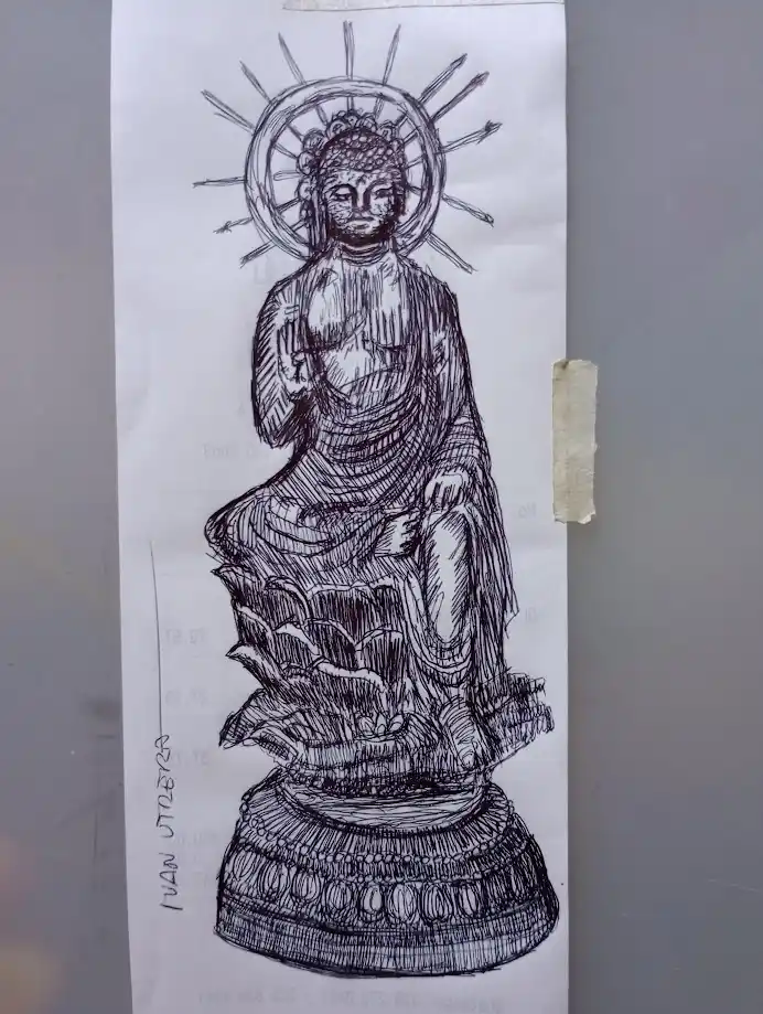 A hand-drawn black-and-white sketch of a seated Buddha statue with a halo and radiating lines, taped to a gray surface. The…