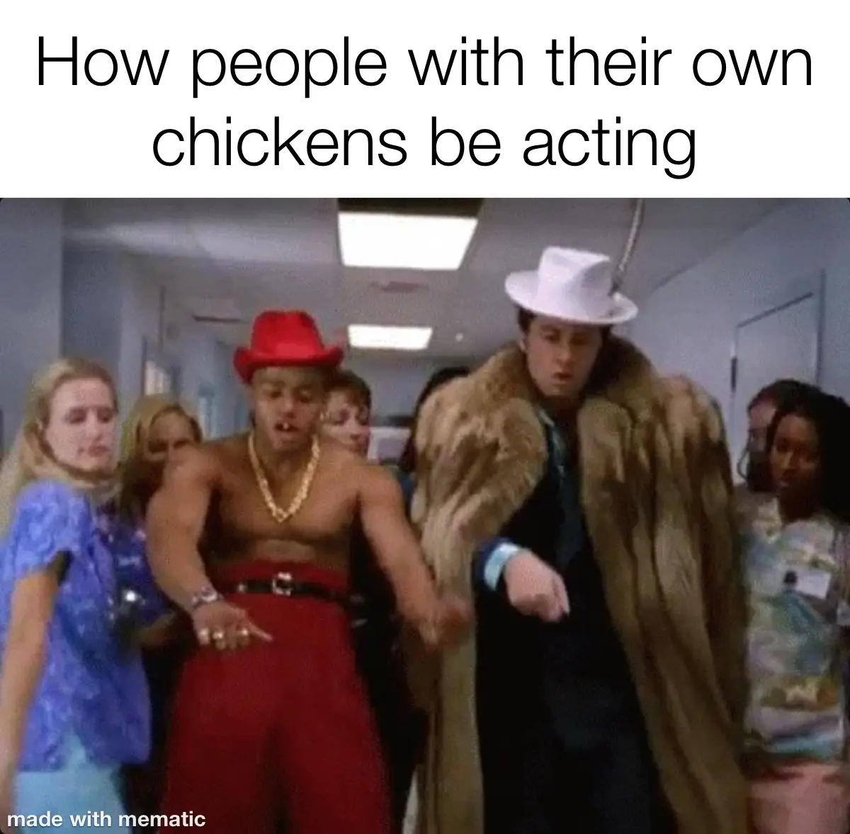A still from a movie shows two men walking down a hallway, one in a red hat and red pants with a gold chain, the other in a…