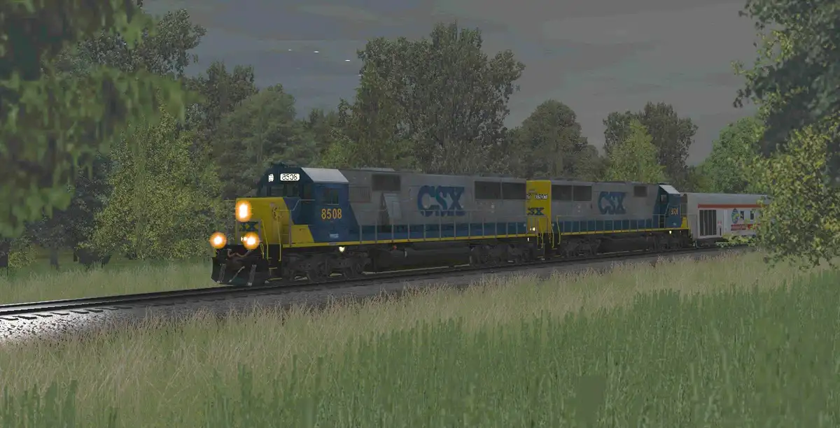 A CSX freight train with locomotives numbered 8508 and 8511 travels through a grassy, tree-lined landscape. The image has…