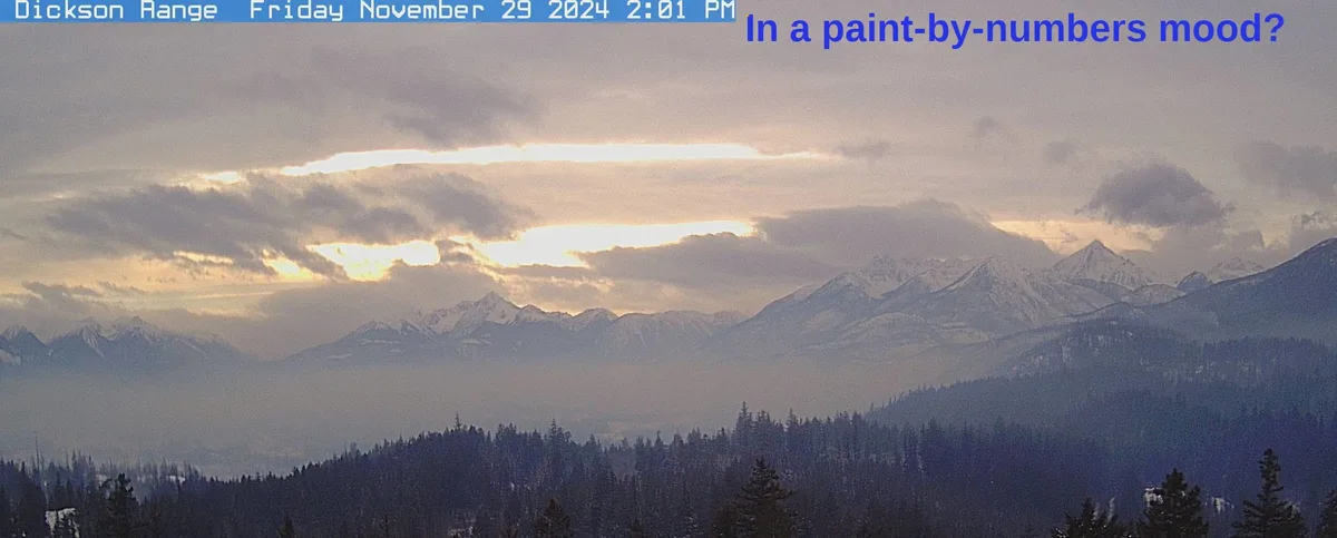 A scenic mountain landscape photo, likely from a weather camera, shows snow-capped peaks under a cloudy sky with sunlight…