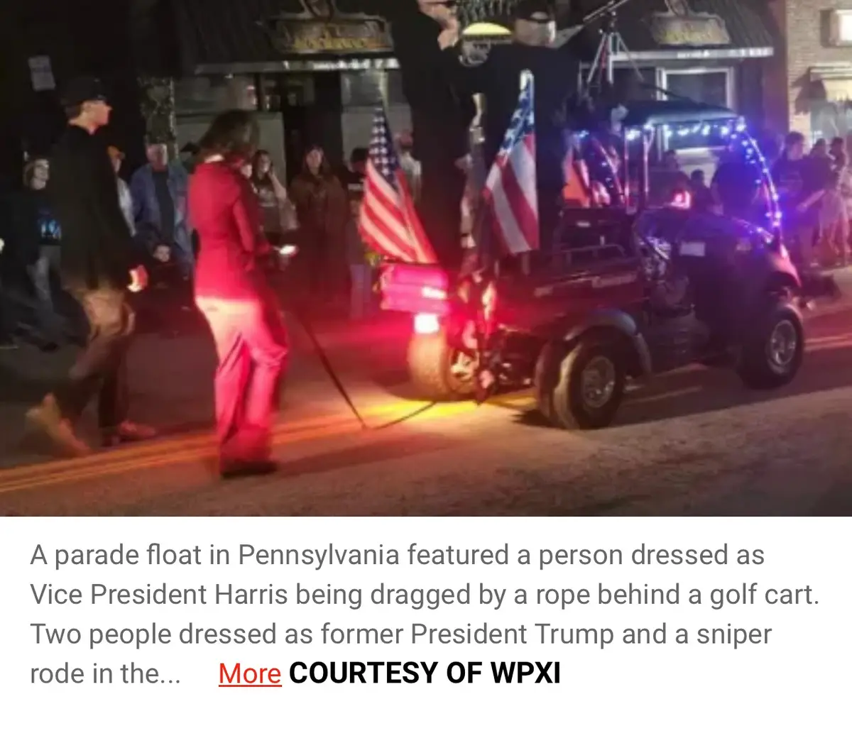 A nighttime parade scene shows a person in a red outfit being dragged by a rope behind a decorated golf cart adorned with…