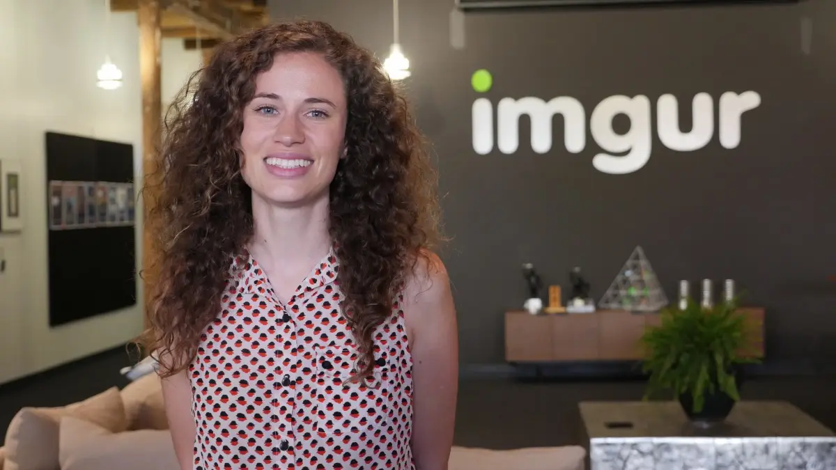 A smiling woman with long curly hair stands in front of an 'imgur' logo on a dark wall. The overlaid text reads 'i'm not a…