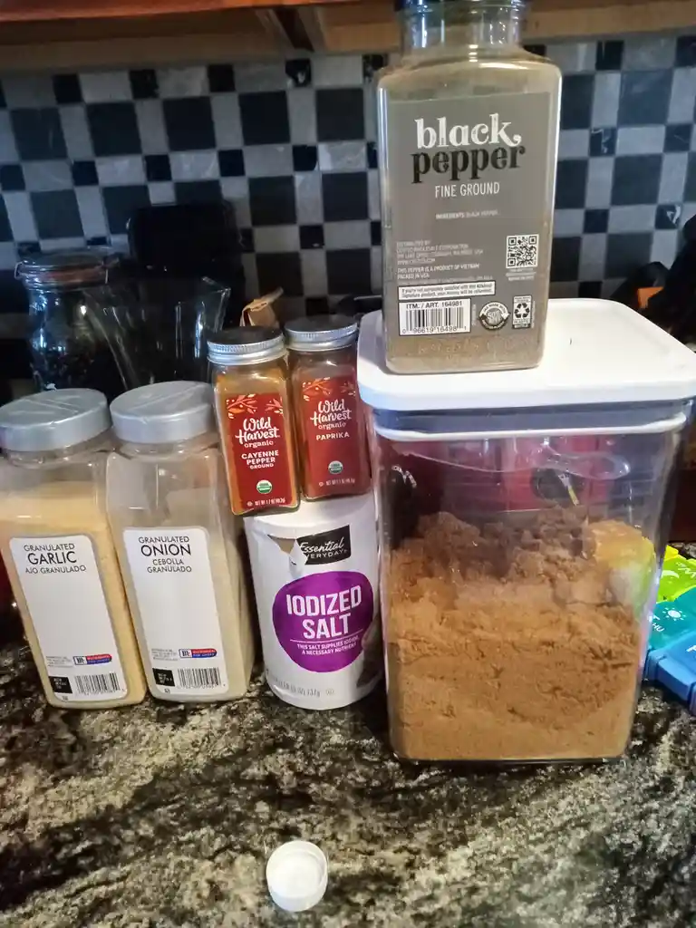 A kitchen counter displays various spice containers including granulated garlic, granulated onion, cayenne pepper, paprika…