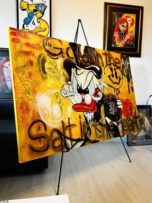 A large, vibrant yellow canvas on an easel features a cartoon duck with a red beak and white feathers, holding a jar labeled…