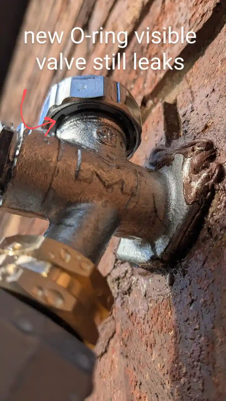 A close-up photo shows a rusty metal valve installed in a brick wall, with water visibly leaking from its side. A red arrow…