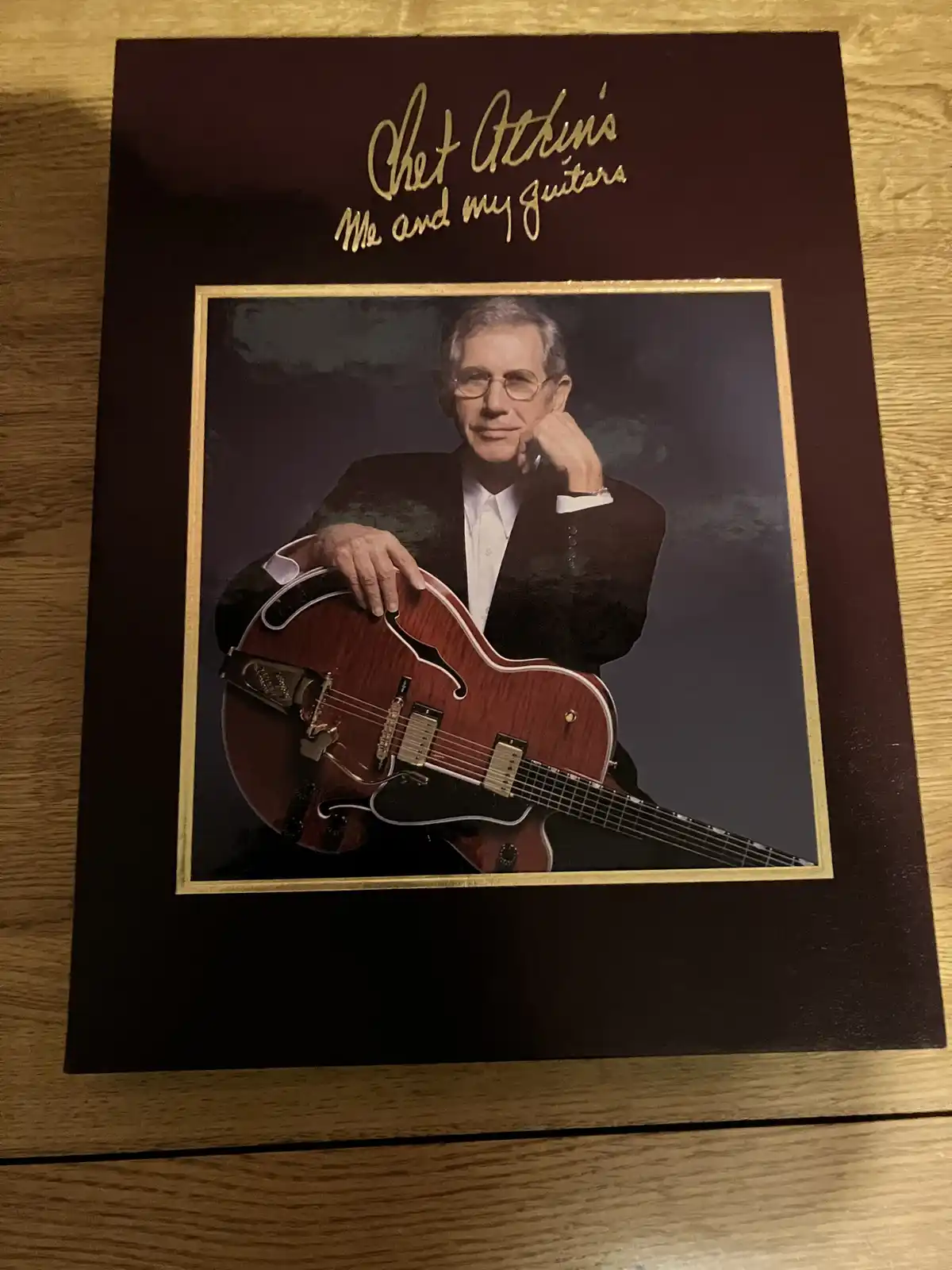 A framed photo of musician Chet Atkins holding a red semi-hollow body electric guitar, with the title 'Chet Atkins Me and my…