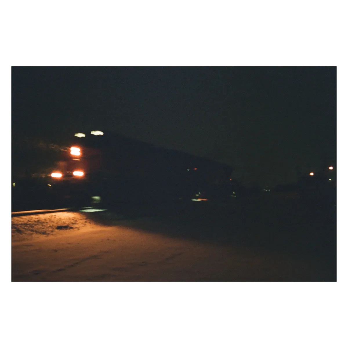 A blurry nighttime photo shows the rear of a vehicle with glowing red taillights, captured from a low angle on a dark road…