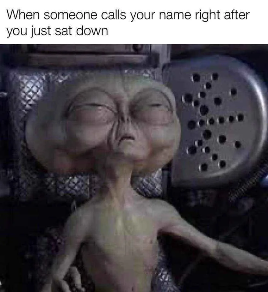 A still image of a green-skinned, large-headed alien with closed eyes, appearing to be resting or dozing off, set against a…
