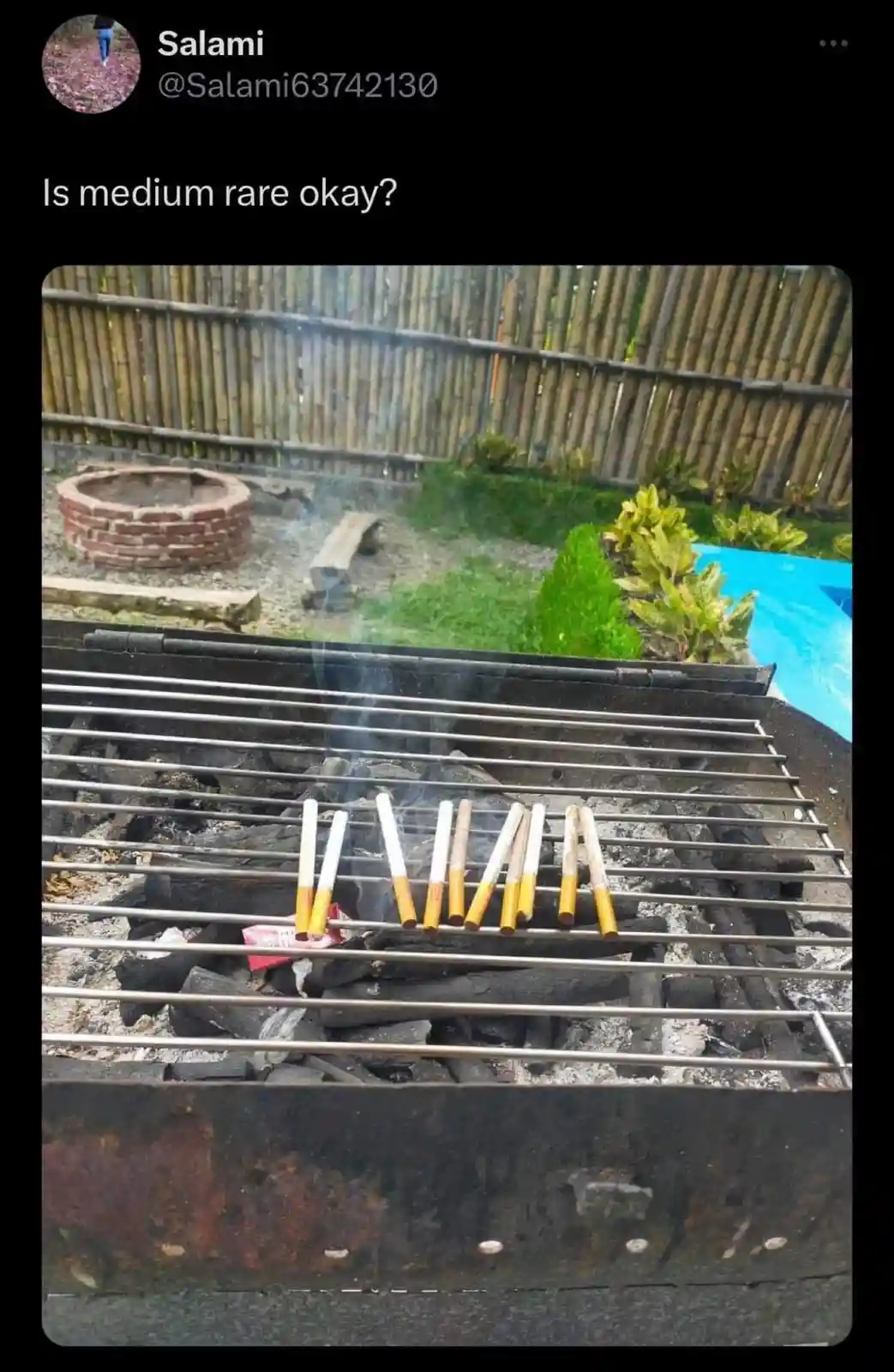 A close-up photo shows several lit cigarettes resting on the metal grates of a charcoal grill, with smoke rising. The…