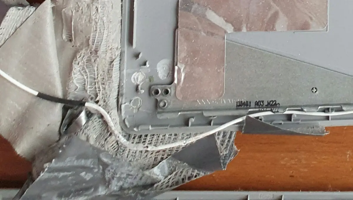 A close-up photo shows the damaged, torn plastic casing of an electronic device, revealing internal wires and components…