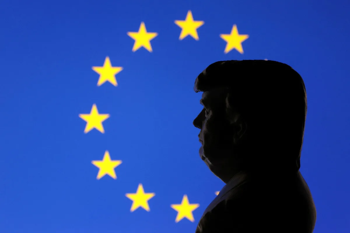 A silhouette of a man resembling Donald Trump is shown in profile against a blurred European Union flag background featuring…