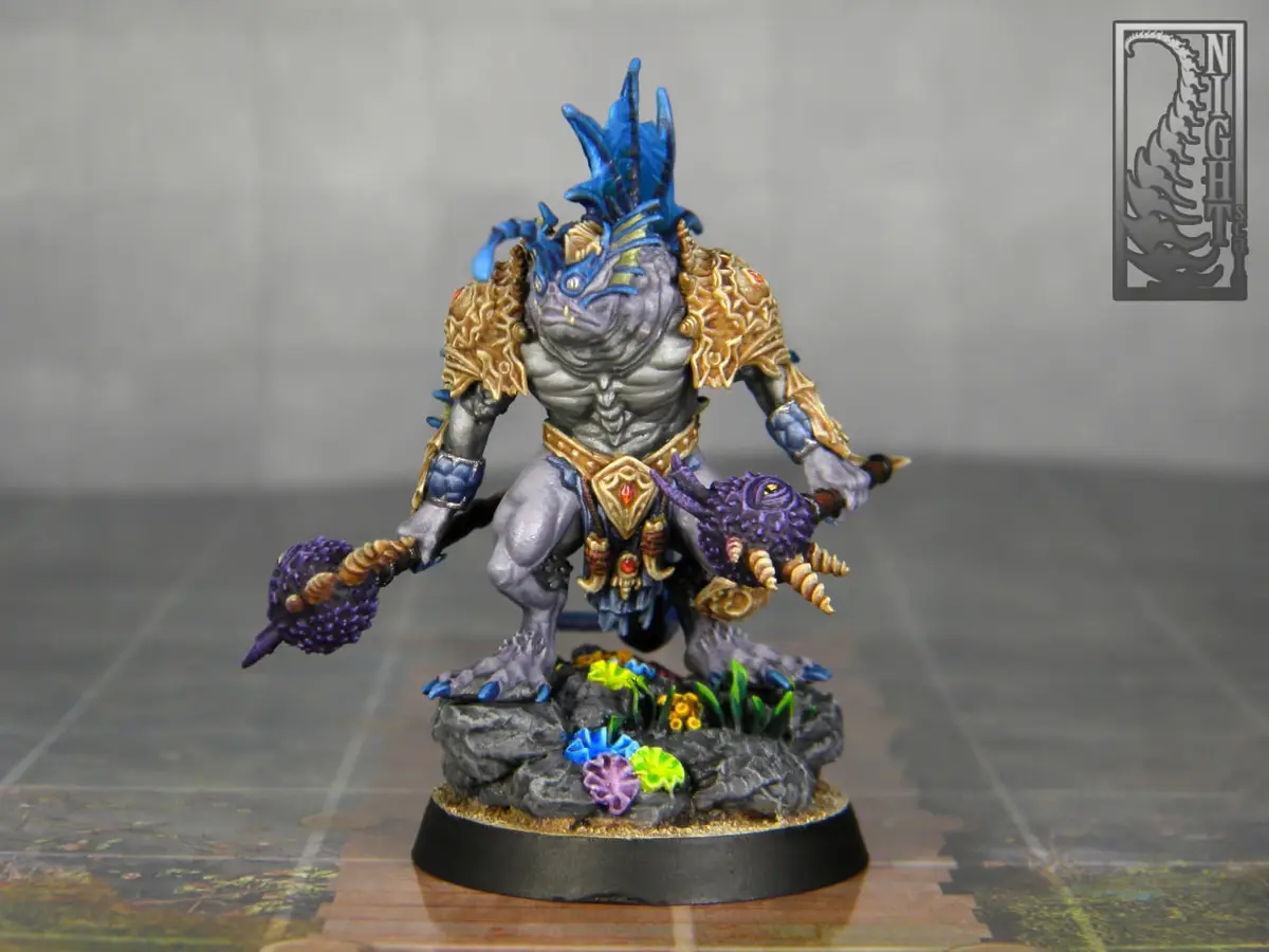 A highly detailed, painted fantasy miniature of a muscular, reptilian humanoid creature with blue spiky hair, gold armor…