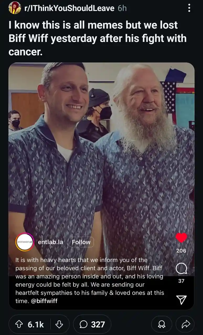 The image shows two men smiling at the camera, one younger with short hair and the other older with a long white beard, both…