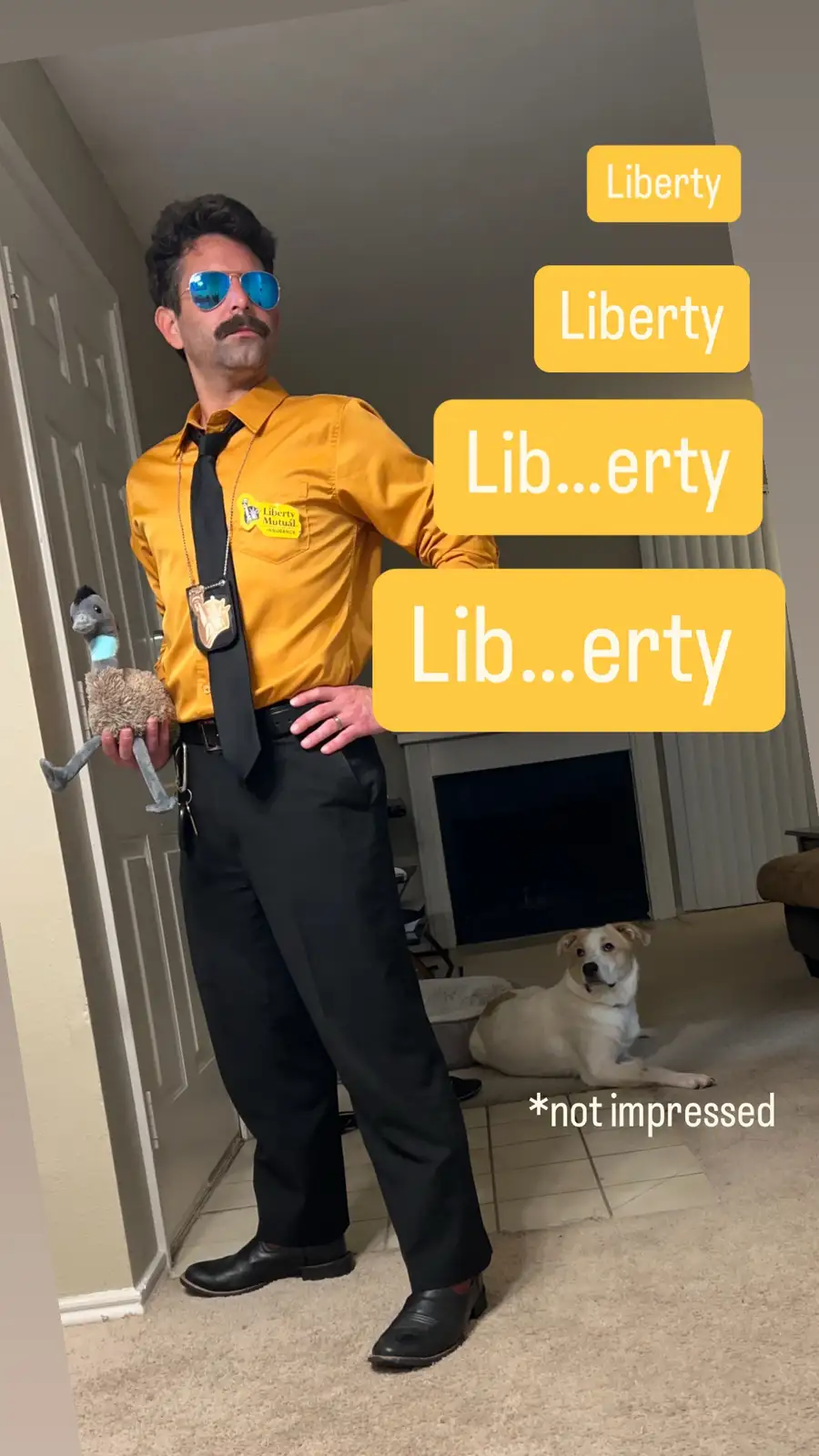 A man dressed as a Liberty Mutual insurance agent, wearing a yellow shirt, black tie, sunglasses, and a mustache, holds a…