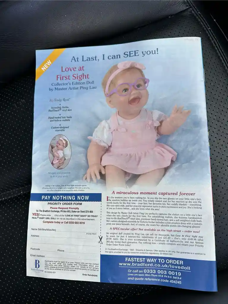 A printed advertisement for a 'Love at First Sight' collector's edition baby doll by Master Artist Ping Lau, featuring a…