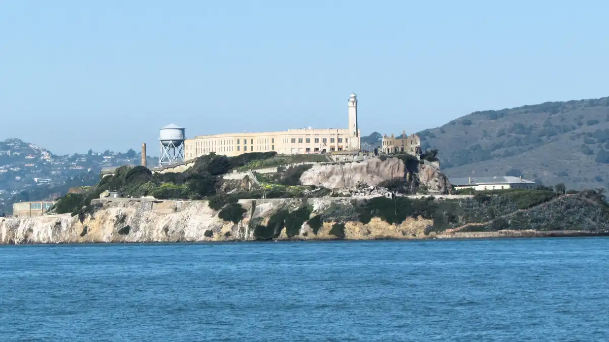 A wide shot of Alcatraz Island in San Francisco Bay, showing the historic prison complex on a rocky island surrounded by…