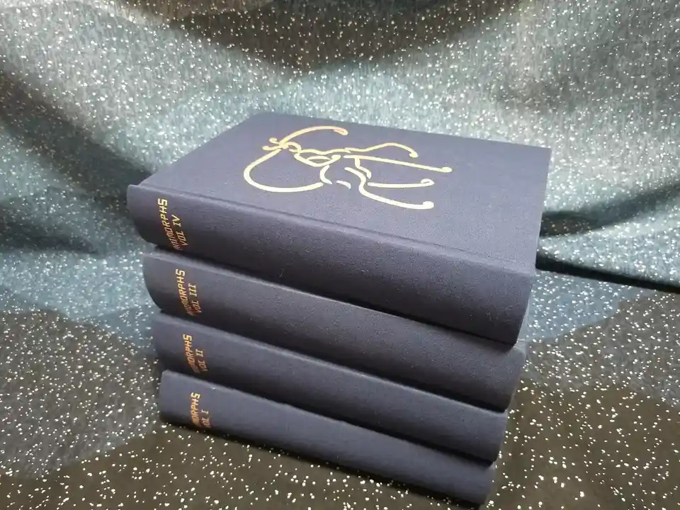 A stack of four dark blue hardcover books titled 'ANTIMORPHS' with volumes I through IV visible on their spines, resting on…