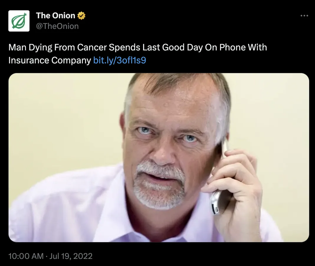 A close-up photo shows a middle-aged man with gray hair and a goatee, wearing a light-colored collared shirt, holding an…