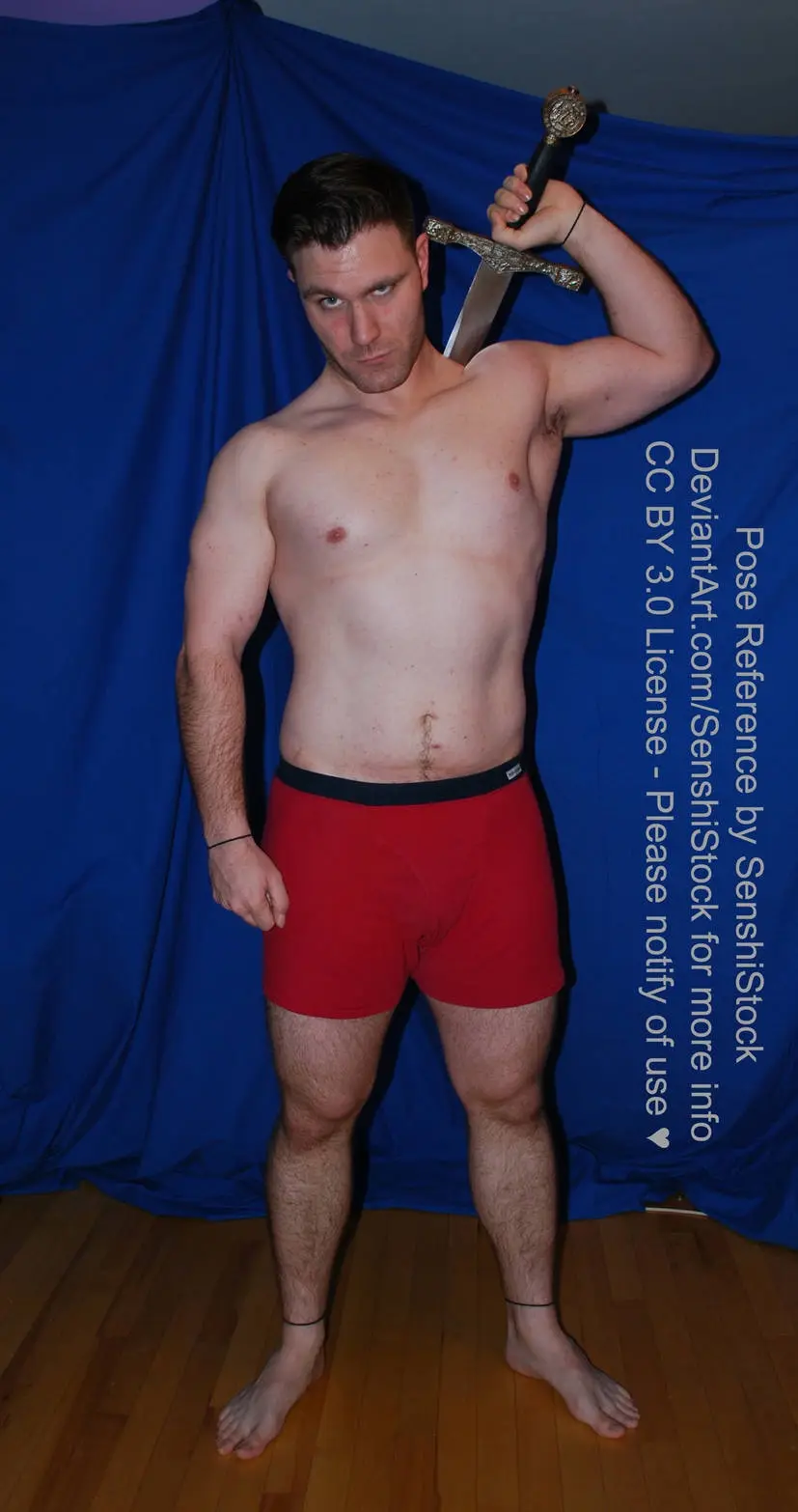 A shirtless man in red boxer briefs stands confidently against a blue backdrop, holding a sword over his shoulder. The image…