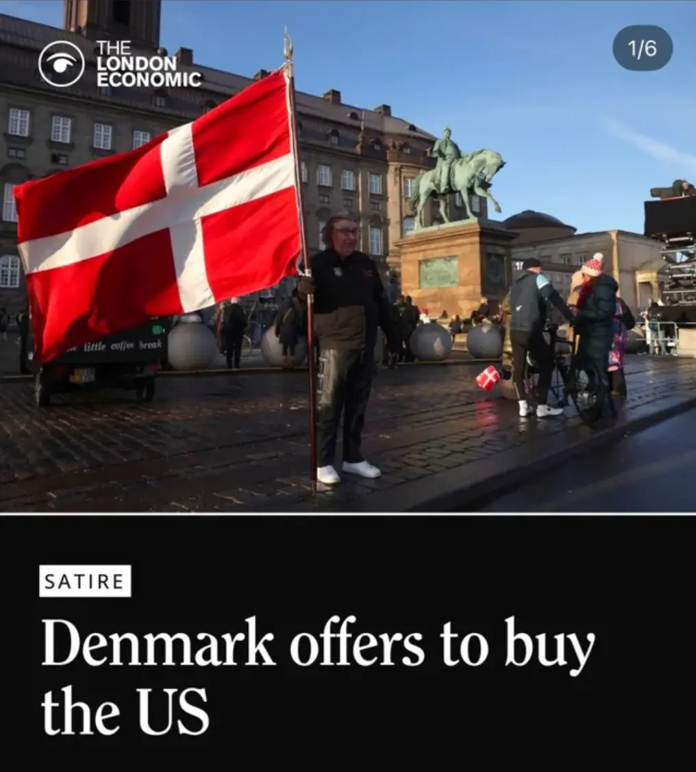 A man stands in a European city square holding a large Danish flag, with a historic building and a bronze equestrian statue…