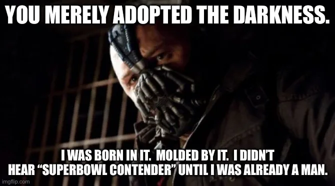 A close-up of the character Bane from Batman, wearing his signature mask and looking intensely at the viewer in a dark…