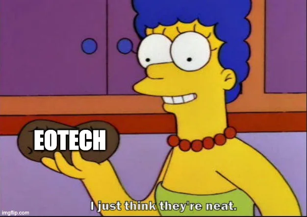 Marge Simpson holds a brown, heart-shaped object with the word 'EOTECH' written on it. She has a wide, slightly manic grin…