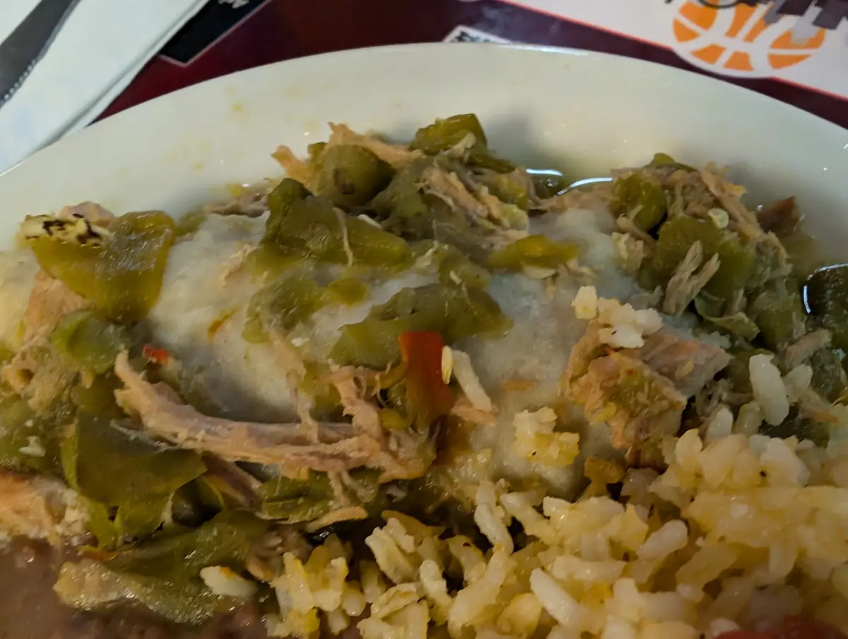 A close-up photo of a plate of food containing shredded meat, green chilies, and rice, with overlaid text reading 'this is…