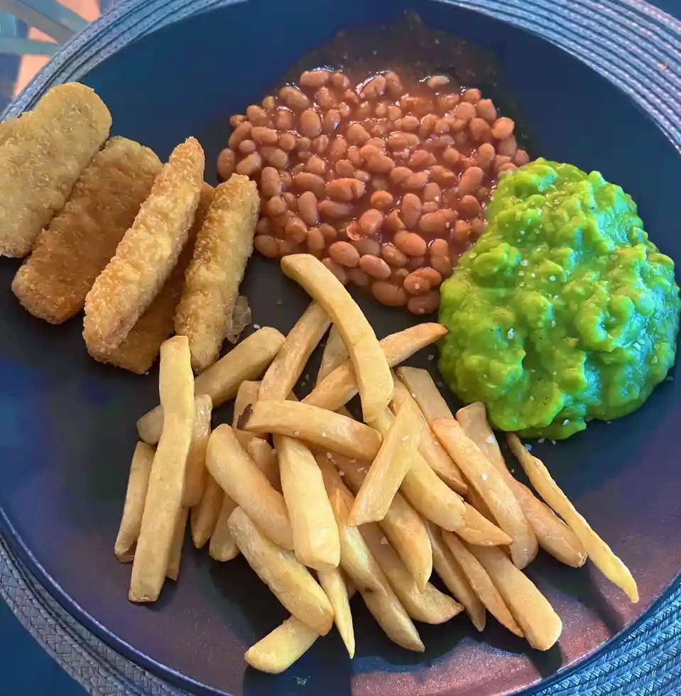 A classic meal: Fish Fingers, Chips, Mushy Peas, and Beans.
