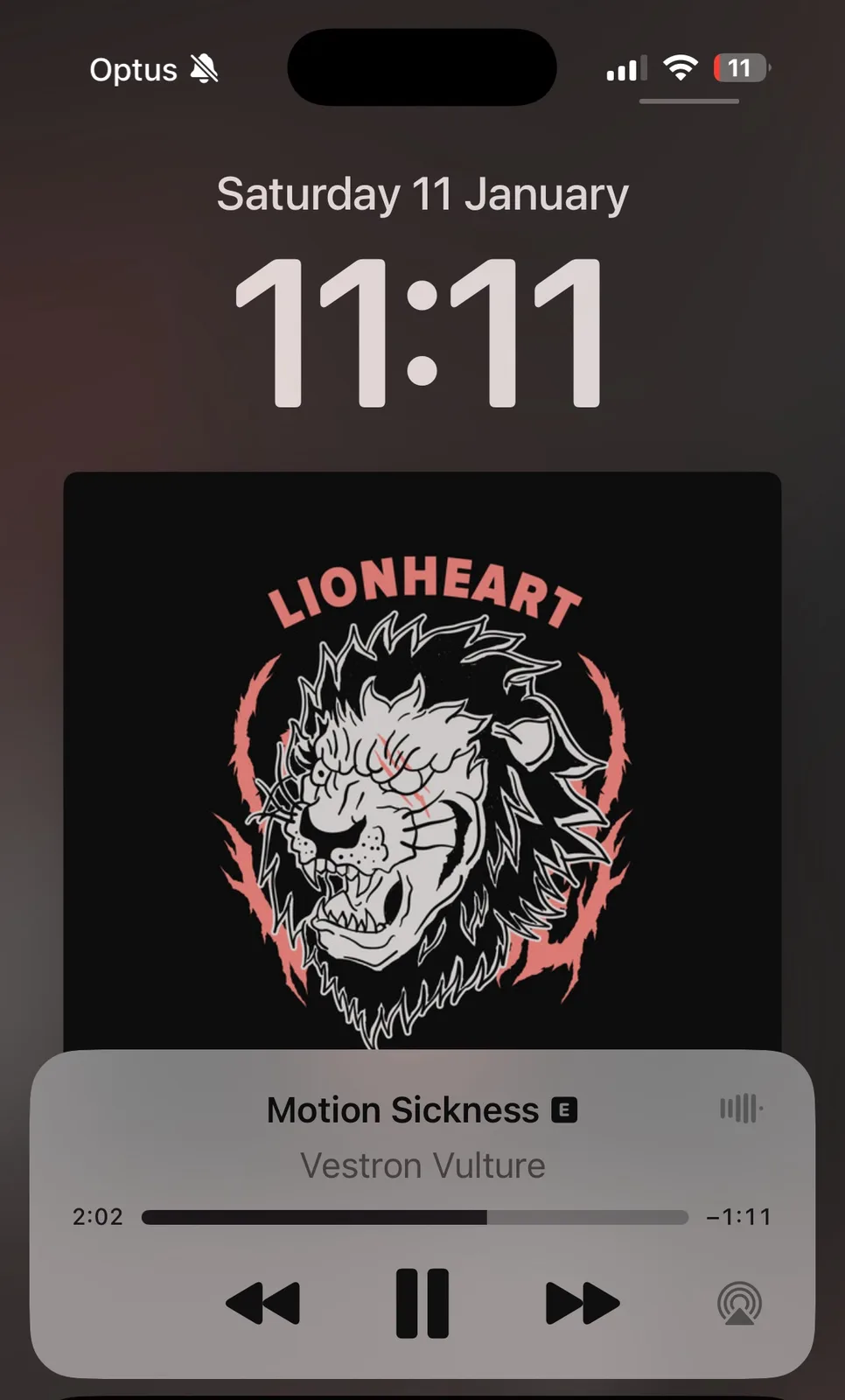 A smartphone lock screen shows the date Saturday 11 January and time 11:11. Below, a music player overlay displays the song…