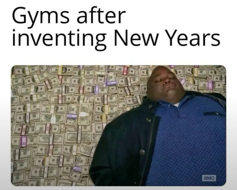 A man in a blue shirt and dark jacket lies with his eyes closed, surrounded by stacks of US dollar bills. The text above…