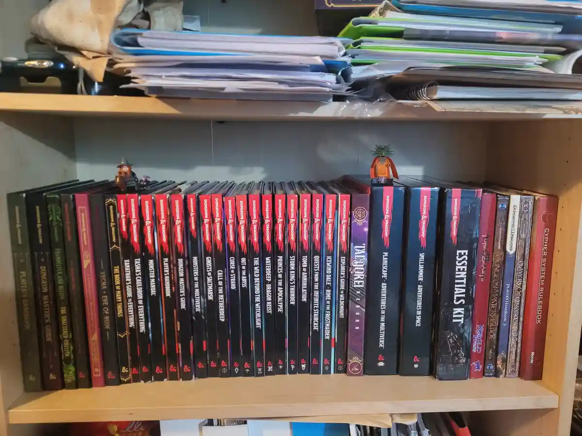 A wooden bookshelf is filled with dozens of Dungeons & Dragons rulebooks and sourcebooks, standing upright in a neat row…