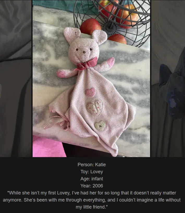 A pink plush bunny lovey toy with a soft blanket attached, featuring embroidered hearts, rests on a marble surface. In the…