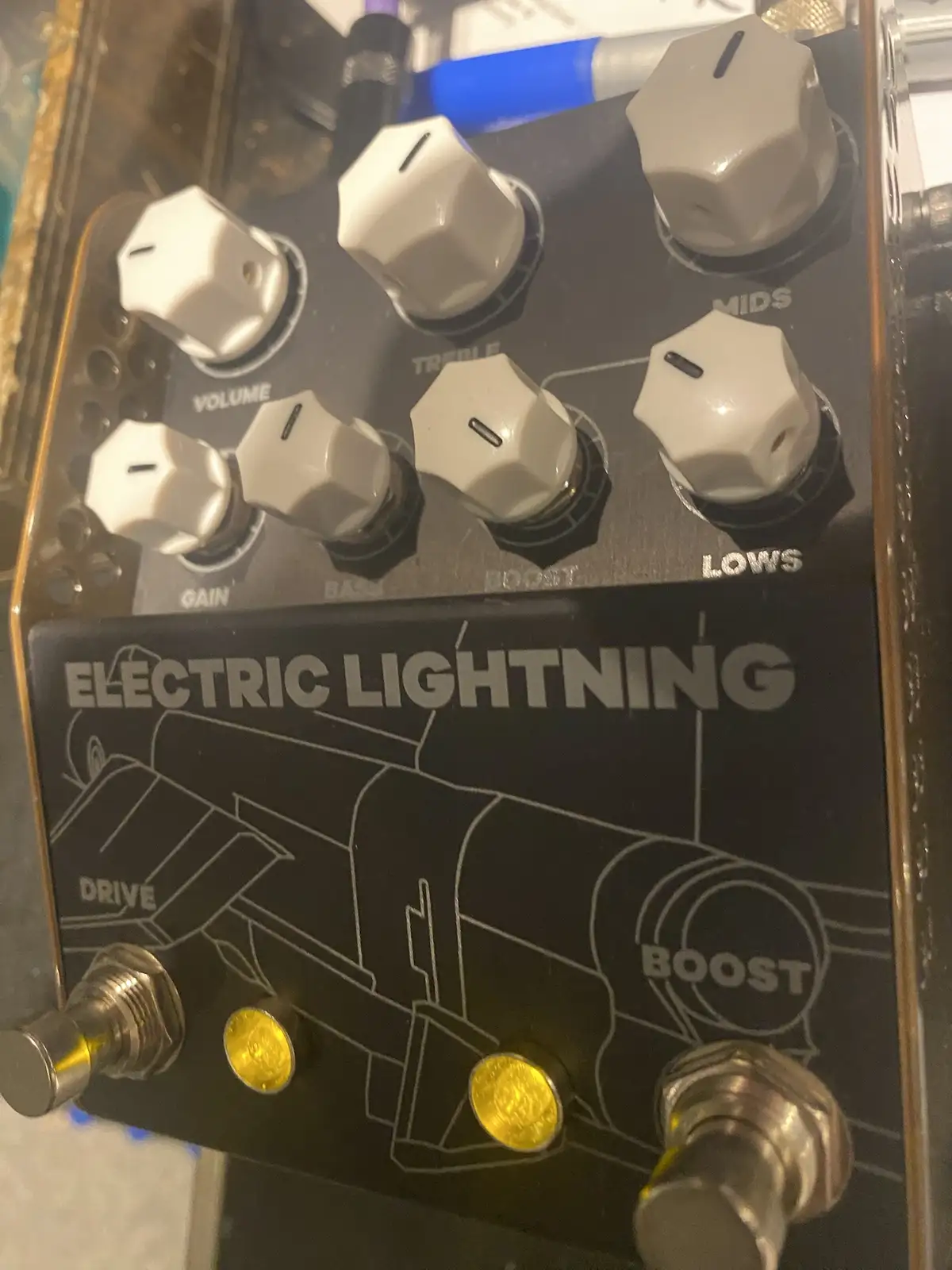 A close-up of a black guitar effects pedal labeled 'ELECTRIC LIGHTNING' with white knobs for volume, gain, bass, treble…