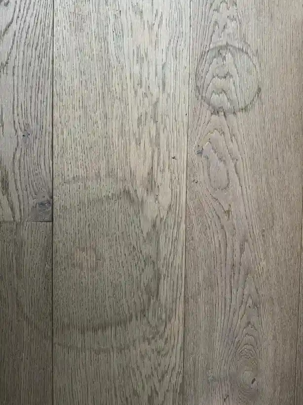 The image shows a close-up of a light gray wooden floor with visible grain patterns and knots. The overlaid text reads 'this…
