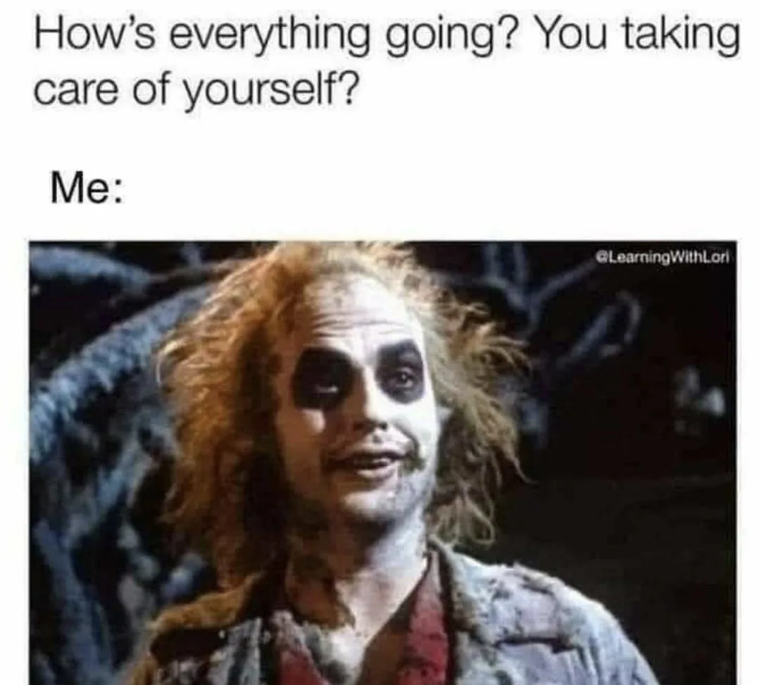 The image shows a close-up of the character Beetlejuice with his signature pale makeup, dark eye circles, and messy red…