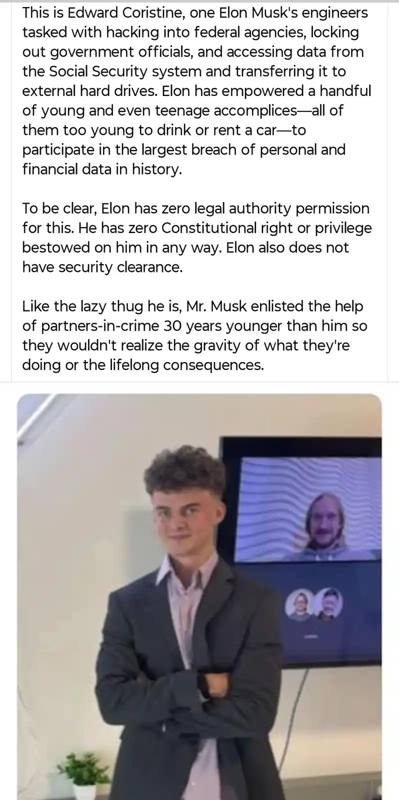 The image shows a young man in a suit standing with arms crossed, looking smugly at the camera. Behind him is a video call…