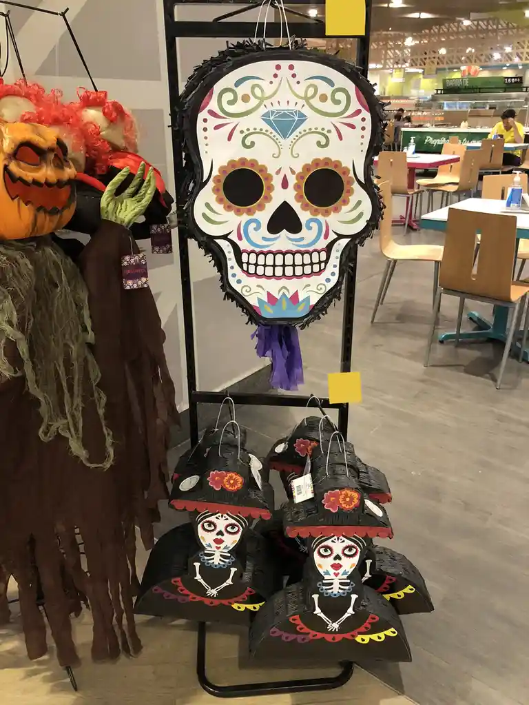 A store display features Halloween decorations including a large, colorful sugar skull piñata with intricate designs and a…