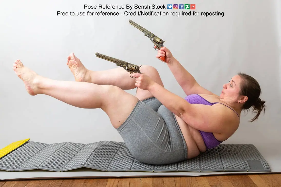 A woman in workout attire is lying on a gray exercise mat, holding two ornate revolvers while performing a sit-up, with her…