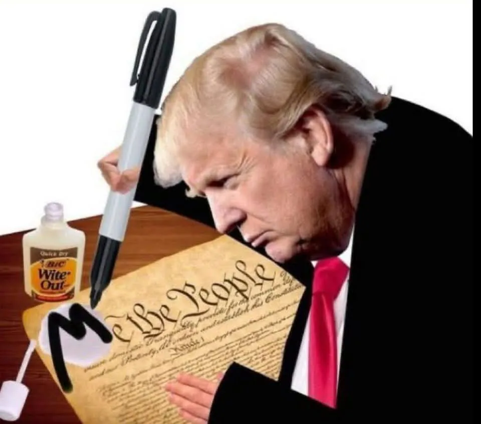 A man with blond hair and a red tie leans over a document resembling the U.S. Constitution, holding a black marker and a…